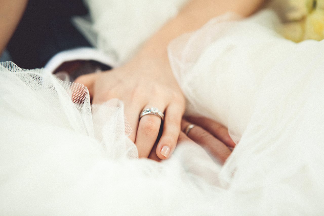 Bride's hands on tulle veil with wedding rings